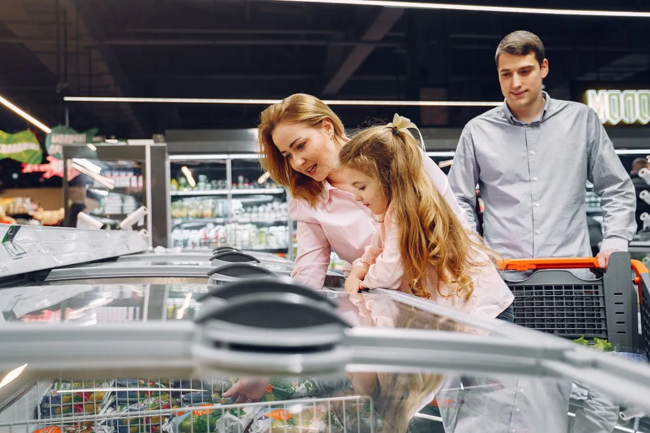 Família escolhendo produtos em um freezer horizontal de supermercado