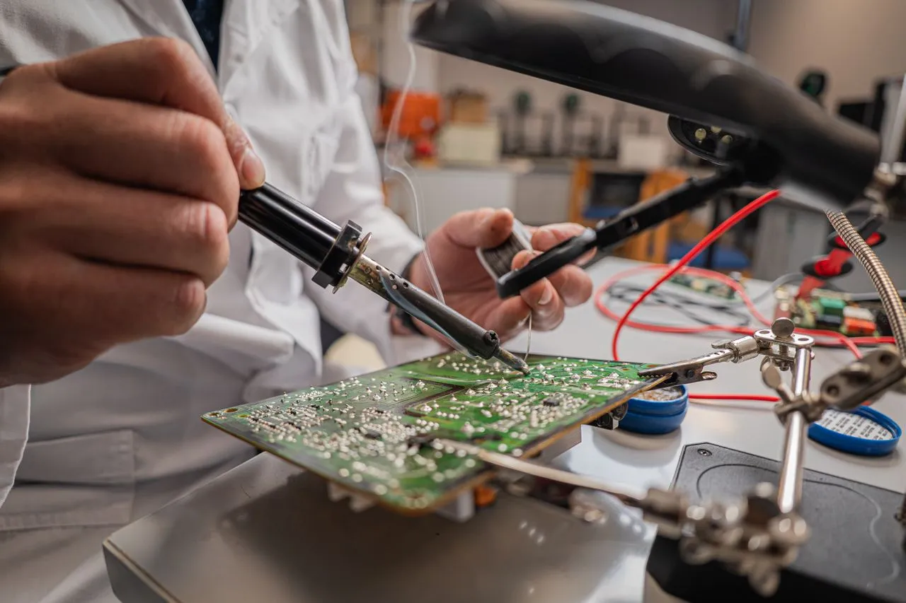 Engenheiro soldando uma placa eletrônica na bancada do laboratório de hardware da Jambo